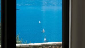 A view of a lake with sailboats, mountains in the background, and a stone wall with a mailbox. - Pearl Mansions (Lefkada)