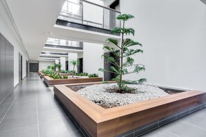 Un atrium intérieur moderne doté d’un jardin central, de plusieurs niveaux et d’un plafond en verre.
