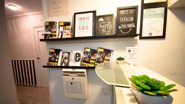 A reception desk with framed motivational posters, a plant, and a sign indicating a business center. - Hostal On Dormire (Valencia)