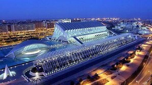 A large, modern cruise ship docked at a port with a distinctive, curved roof structure and multiple decks. - Hostal On Dormire (Valencia)