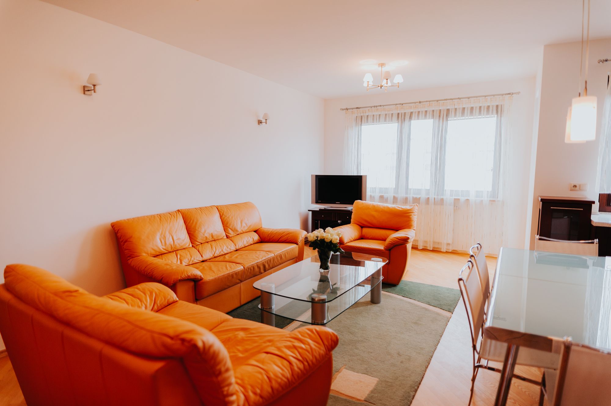 Ein Wohnzimmer mit Sofa, Sessel, Couchtisch und Fernseher.