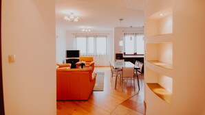 A modern living room with a sofa, TV, and dining area. - Elite Apartments Jelitkowski Dwor (Gdansk)