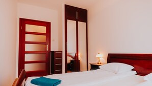 A hotel room with a bed, a wardrobe, a nightstand, and a lamp. - Elite Apartments Jelitkowski Dwor (Gdansk)