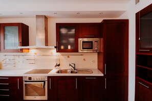 Apartamento, 2 quartos | Cozinha americana privada | Geladeira, micro-ondas, fogão, cooktop