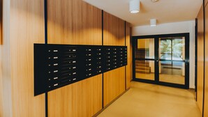A modern hallway with wooden paneling, a black filing cabinet, and a glass door leading to a staircase. - Elite Apartments Nature & Recess (Gdansk)