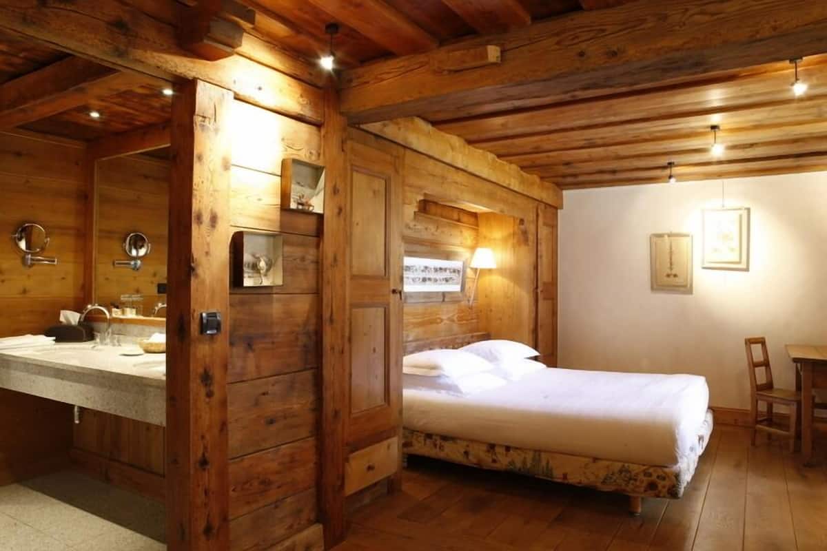 A wooden cabin-style room with a bed, a small table, and a chair.