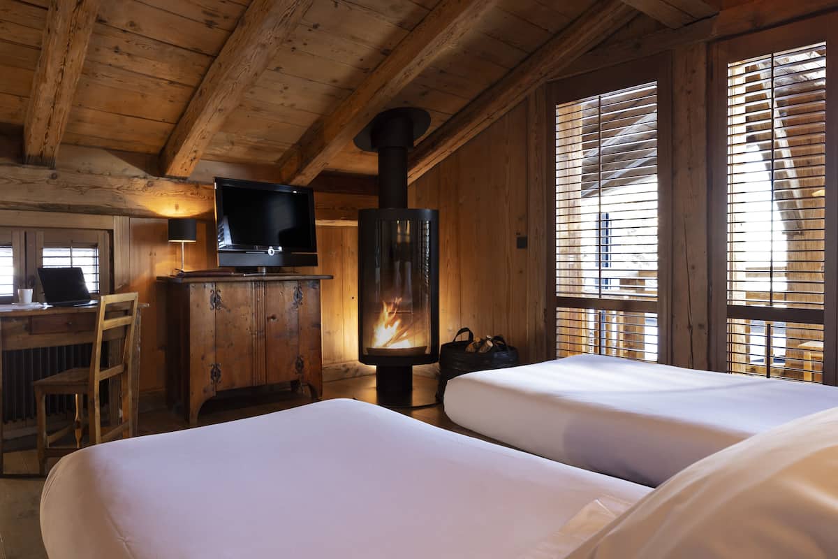 A cozy room with a fireplace, wooden walls, a TV, and two beds.
