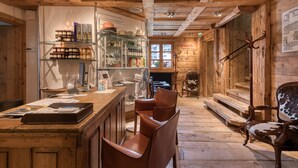 Un intérieur rustique en bois, avec un coin bar, des fauteuils en cuir et une cheminée.