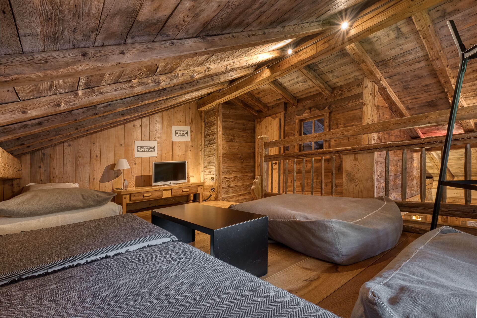 Une chambre confortable située dans les combles, avec des murs en bois, un lit, un bureau et une télévision.