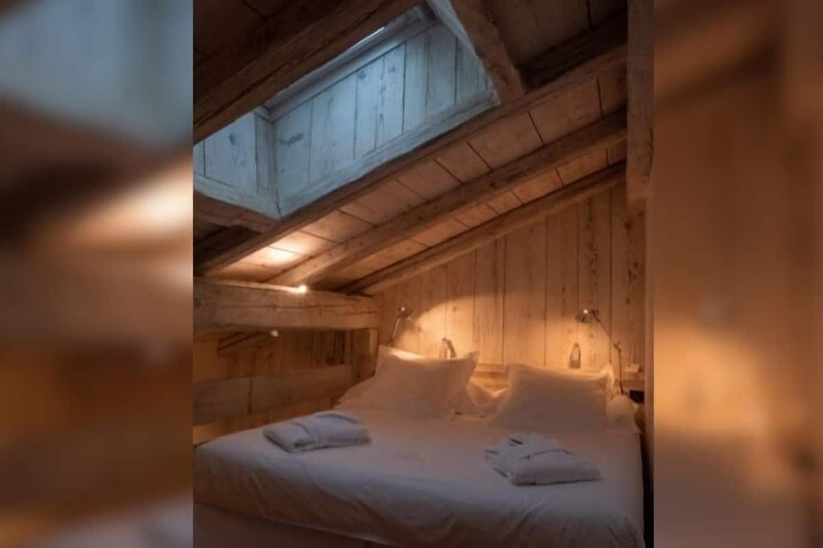 A cozy wooden cabin room with a bed, two bedside tables, and a skylight.