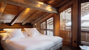 Un plafond en bois avec des poutres apparentes et un lit recouvert de draps blancs.
