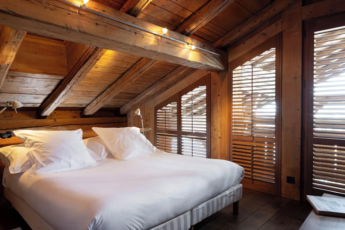 A wooden ceiling with exposed beams and a bed with white linens.