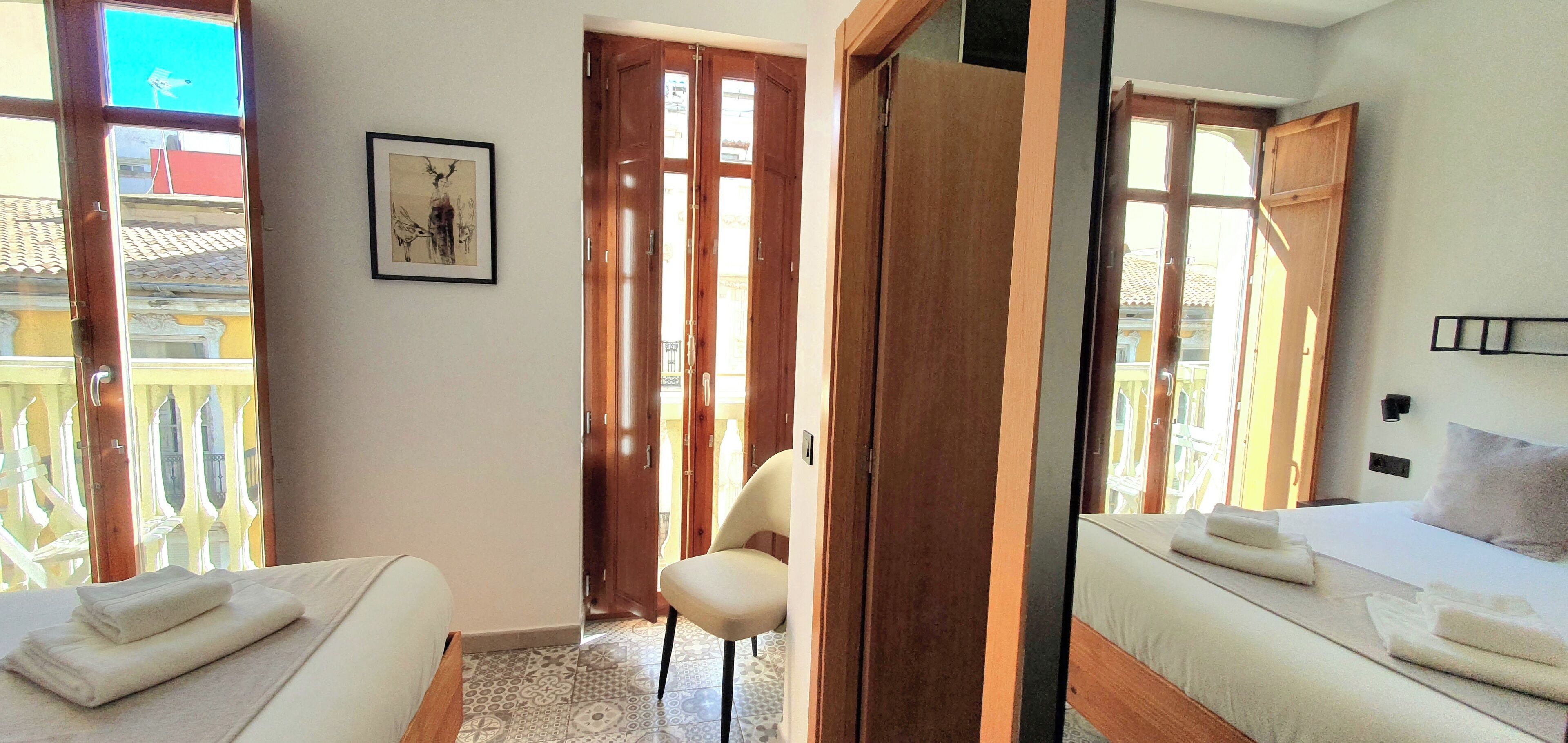 Una camera d'albergo con due letti, una sedia e una porta in legno.