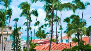 A coastal resort with palm trees and buildings with red-tiled roofs. - The Sanctuary at Los Corales (Punta Cana)