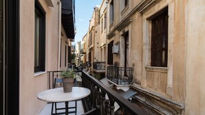 A narrow alleyway with a small table and chair, a potted plant, and a railing. - Nonnalena Hotel (Chania)