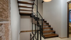 A modern staircase with wooden steps and black metal railings, leading to an upper floor. - Nonnalena Hotel (Chania)