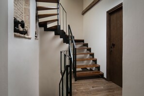Una escalera con escalones de madera y barandillas de metal negro, que conduce a una puerta de madera.