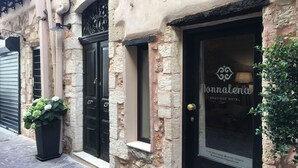 A boutique hotel with a stone facade, black doors, and a sign reading "Nonnalena Boutique Hotel". - Nonnalena Hotel (Chania)