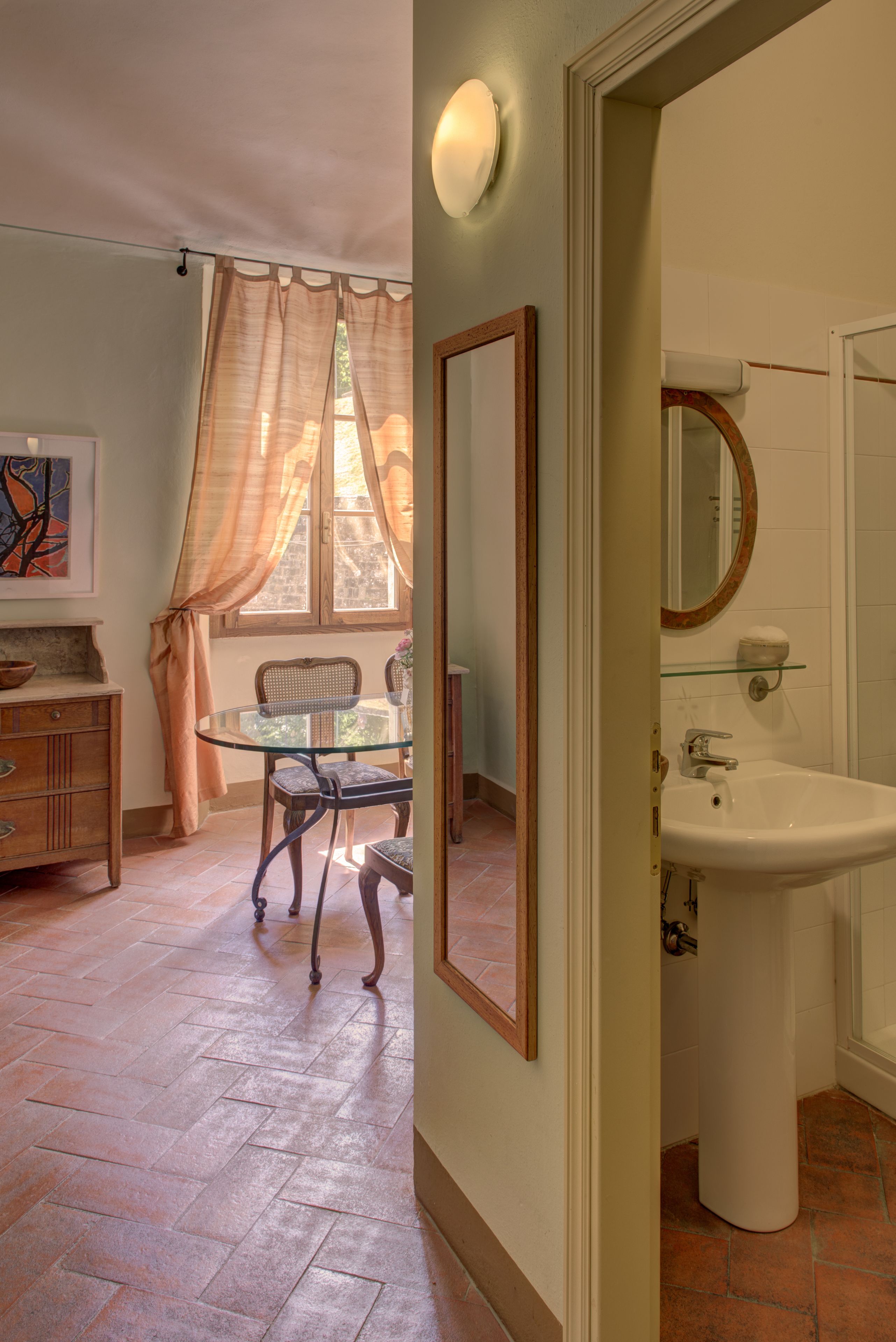 A bathroom with a white sink, a mirror, and a window with curtains.