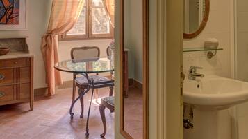 A bathroom with a white sink, a mirror, and a window with curtains.