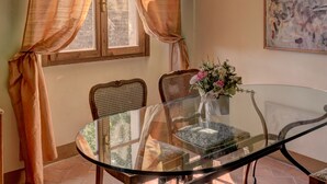 A dining area with a glass table, two chairs, a vase with flowers, and a painting on the wall. - Albergo San Lorenzo (Poppi)