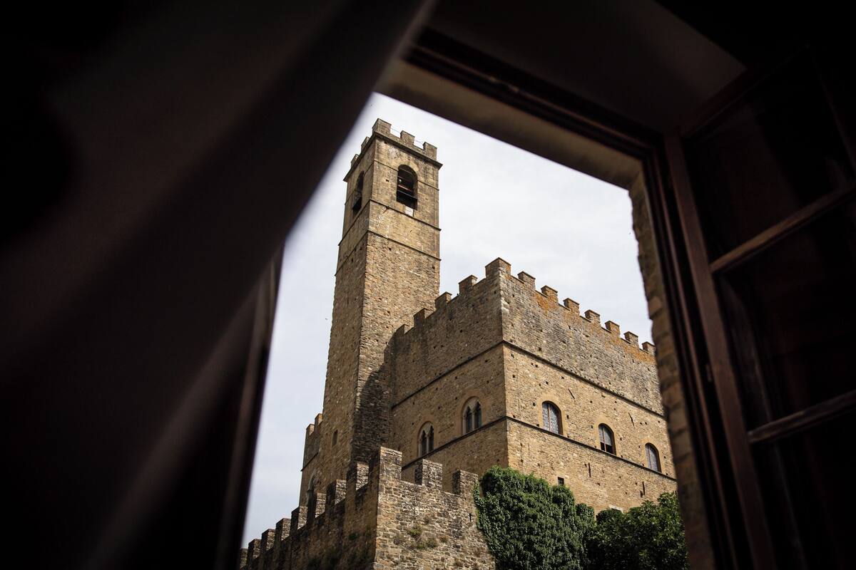 A historic stone tower viewed through an open window, with a clear sky in the background.