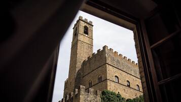 Una torre de piedra histórica visible a través de una ventana abierta, con un cielo despejado al fondo.