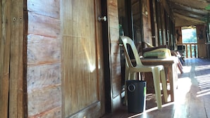 A wooden door with a metal handle, a plastic chair, and a trash bin on a wooden floor. - Kopi Doki Guest Haus (Coron)
