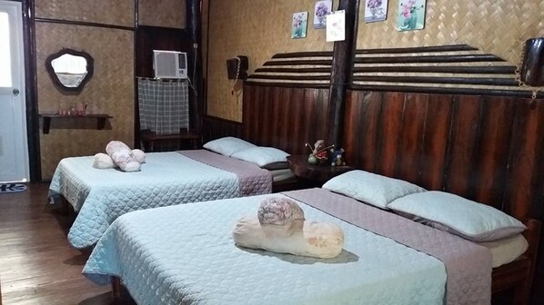 A hotel room with two beds, a wooden headboard, a mirror, an air conditioning unit, and a small shelf with decorative items. - Kopi Doki Guest Haus (Coron)