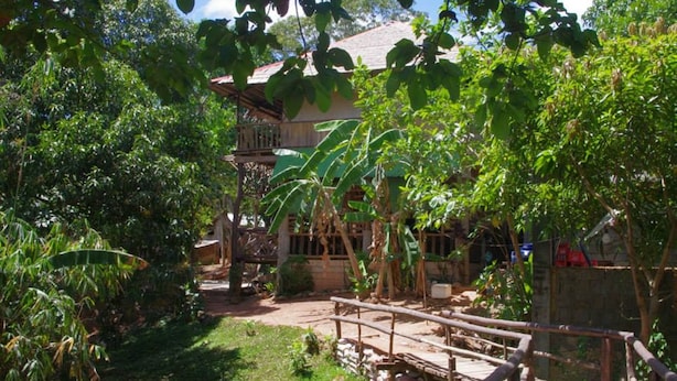 A rustic wooden bridge leading to a house surrounded by lush greenery and banana trees. - Kopi Doki Guest Haus (Coron)