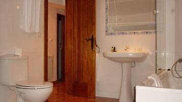 A bathroom with a toilet, sink, and mirror.