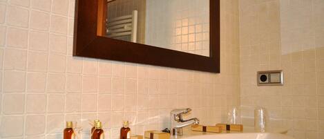 A bathroom with a white sink, a mirror, and toiletries.