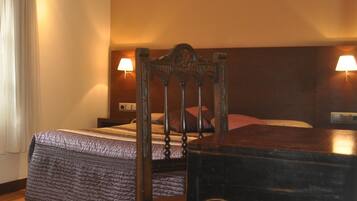 Una habitación de hotel con una cama, una silla, una mesa y dos lámparas de noche de madera.