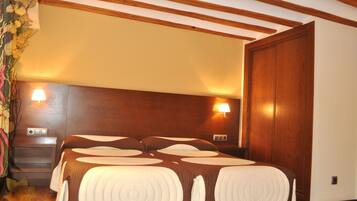Ein Hotelzimmer mit einem großen Bett, einem Holzkopfteil, zwei Nachttischlampen und einem Schrank aus Holz.