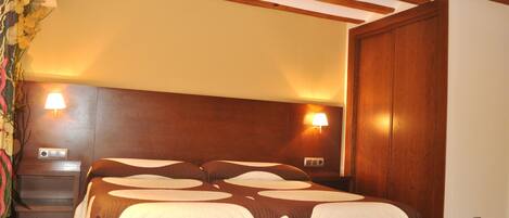A hotel room with a large bed, wooden headboard, two bedside lamps, and a wooden wardrobe.