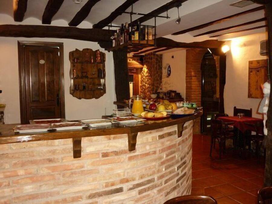 Un rústico bar con mostrador de ladrillo, vigas de madera y pared de piedra.