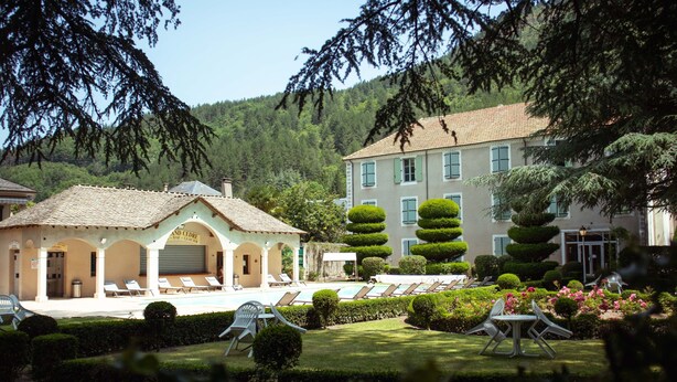 A hotel with a pool area, sun loungers, and a well-maintained garden. - Grand Hôtel du Parc (Florac)