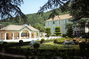Um hotel com área de piscina, espreguiçadeiras e um jardim bem cuidado.