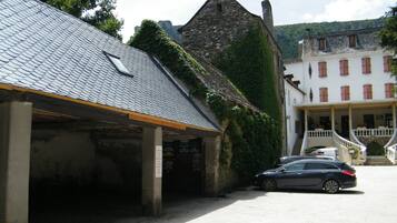 Un edificio con facciata in pietra, un'area di parcheggio coperta e una scala che conduce al secondo piano.