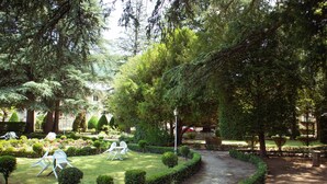 A well-maintained garden with neatly trimmed hedges, a curved pathway, and outdoor seating with white chairs. - Grand Hôtel du Parc (Florac)