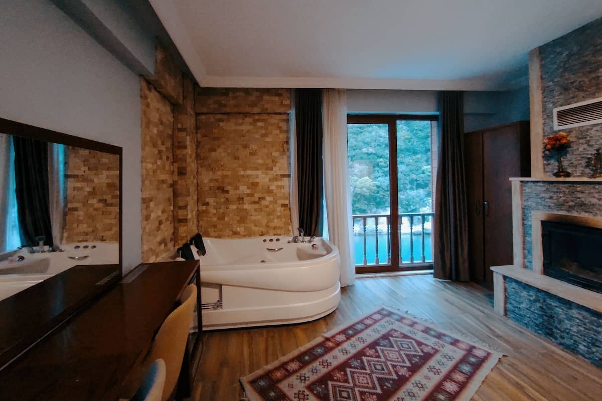 A modern bathroom with a bathtub, a vanity with a mirror, and a large window with a view of trees.