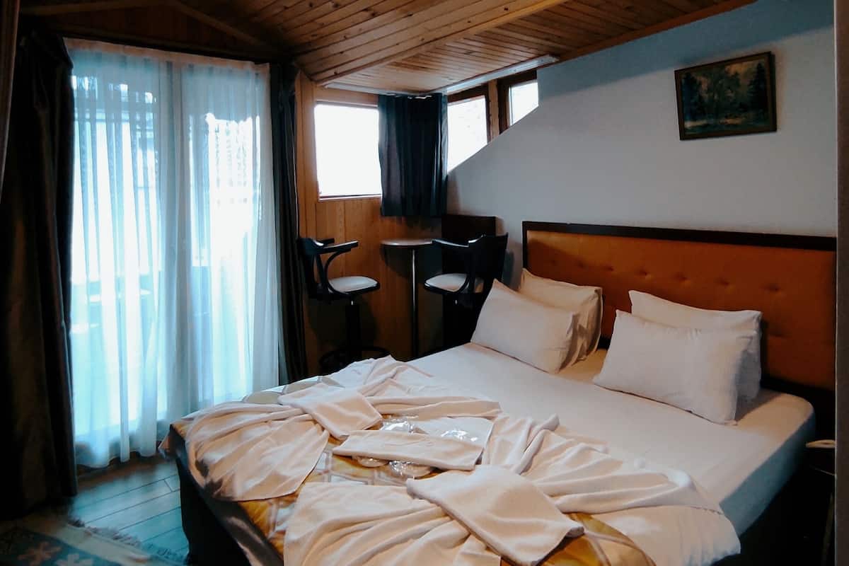 A wooden-paneled room with a bed, a desk, and a chair.