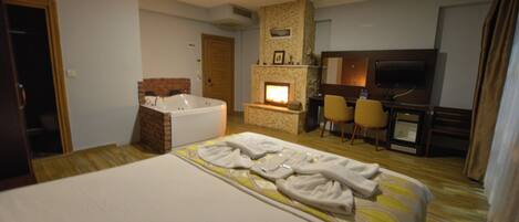Habitación de hotel con una cama grande, baño independiente, chimenea, televisor y escritorio.