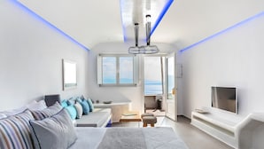 Un saló modern amb un sofà, una televisió i vista al mar.