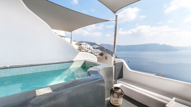 Zona de piscina amb vistes al mar i edificis blancs al fons.