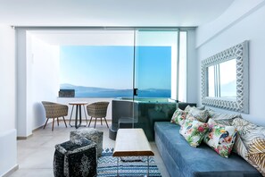 A modern living room with a sofa, chairs, a coffee table, and a view of the ocean. - Santorini Secret Premium (Santorini)