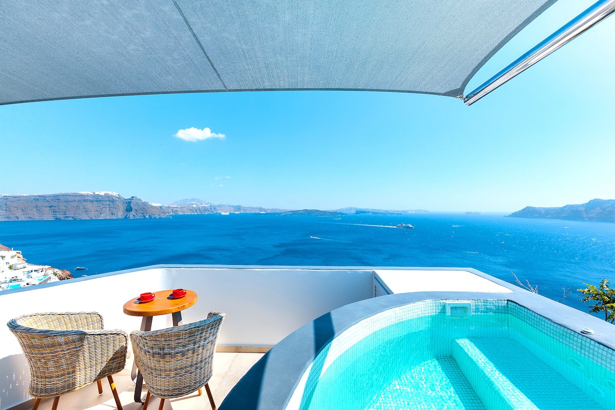 A balcony with a view of the sea, a small pool, and wicker chairs.