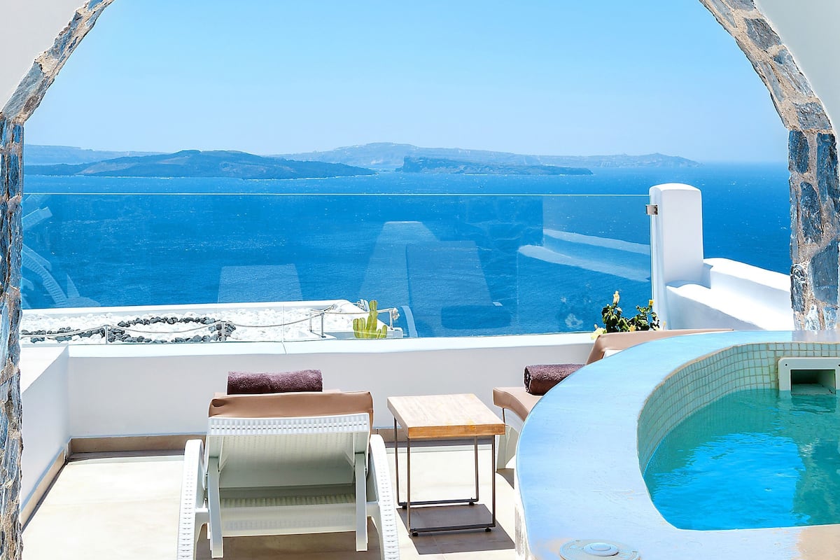 A sunlit terrace with a pool, lounge chairs, and a view of the sea.