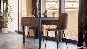 Un comedor moderno con una mesa y sillas, ventanas amplias con cortinas y una planta en maceta.