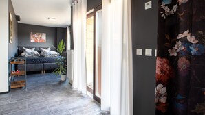 Una sala moderna con un sofá gris, una planta en maceta y un ventanal grande.